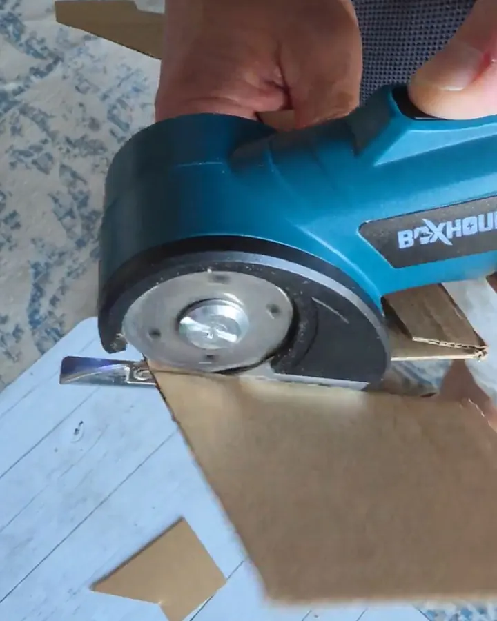 Close-up of an adult holding the blue Boxhound with its work light illuminating the cardboard