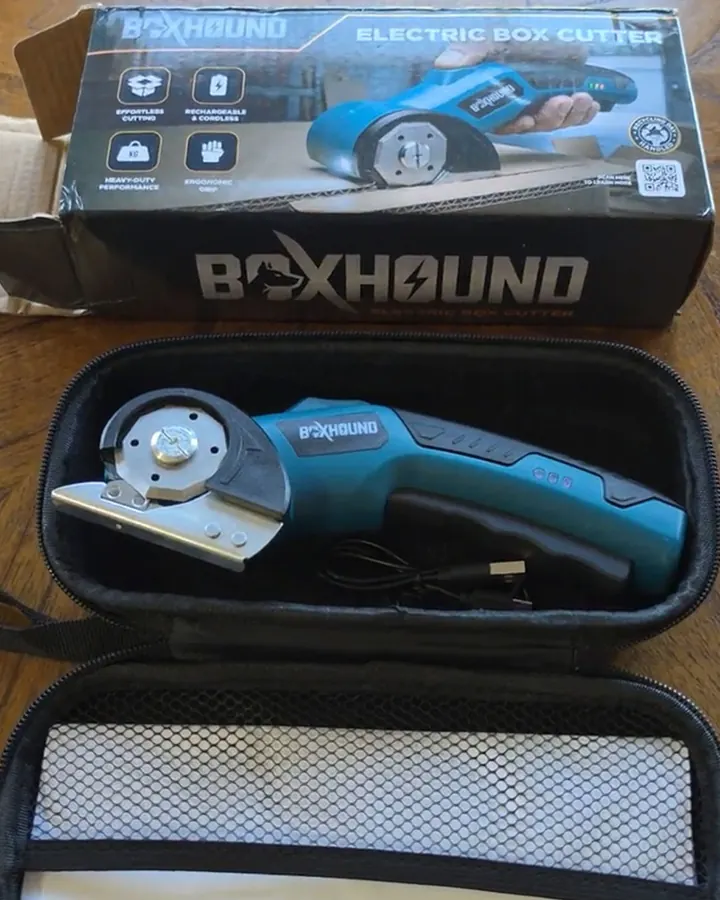 The blue Boxhound electric box cutter beside its branded retail box, cable, blade, and manual